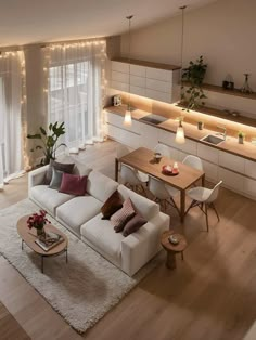 a living room filled with white furniture and lots of lights on the wall above it