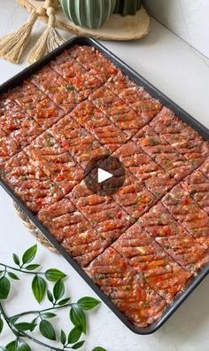 a pan filled with meat sitting on top of a table next to a plant and potted