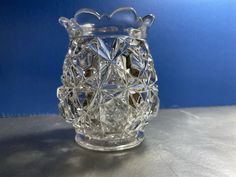 a clear glass vase sitting on top of a metal table next to a blue wall