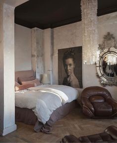 a bedroom with a bed, chair and pictures on the wall in it's corner