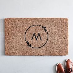 a pair of shoes sitting on top of a door mat next to a person's feet