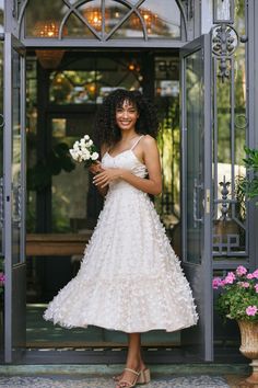 a woman in a white dress is standing at the entrance to a building with flowers