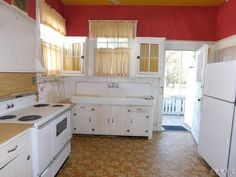 a kitchen with white appliances and red walls