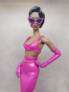 a barbie doll wearing pink leather clothes and sunglasses with her hands on her hips, posing for the camera