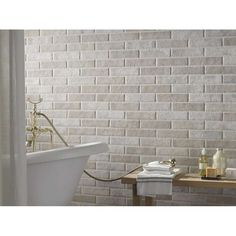 a bath tub sitting next to a white brick wall