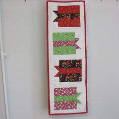 a wall hanging on the side of a white door with red and green ribbons attached to it