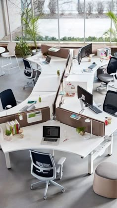 an office cubicle with multiple desks and chairs in the center, along with two computers