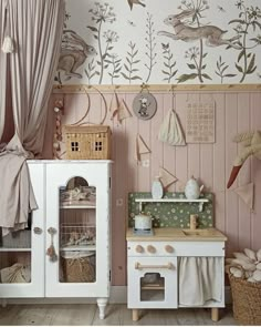 a child's play kitchen with pink walls and floral wallpaper