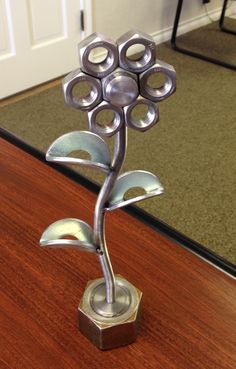 a metal flower sculpture sitting on top of a wooden table