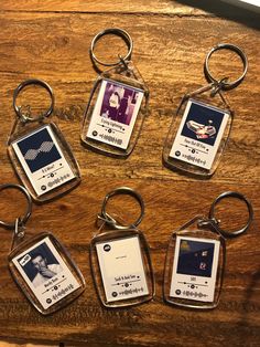 six keychains with different pictures on them sitting on a wooden table next to each other