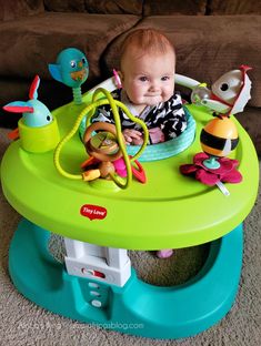 a baby sitting in a play table with toys