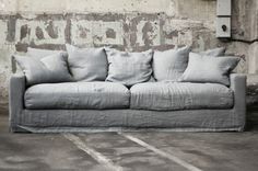 a couch sitting in front of a brick wall with lots of pillows on top of it