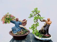 two figurines sitting on top of a table next to each other with plants growing out of them