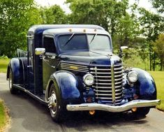 an old fashioned truck is driving down the road in front of some grass and trees