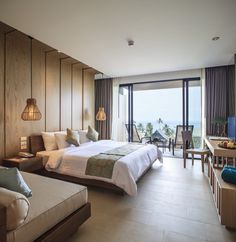 a hotel room with a large bed and balcony overlooking the ocean in front of a sliding glass door