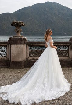 a woman in a wedding dress is standing near the water