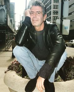 a man sitting on top of a cement planter