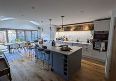 an open kitchen and dining room area with wood floors, white walls, and skylights