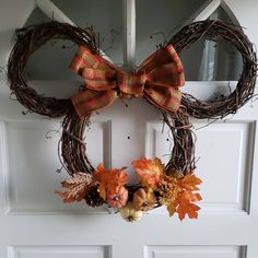 a wreath with an orange bow and fall leaves is hanging on the front door,