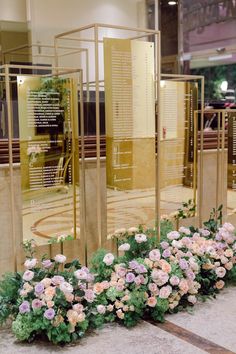 some flowers are sitting in front of three gold pillars with names on them and plants growing out of the sides