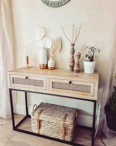 a white table with baskets and vases on it next to a wall mounted mirror