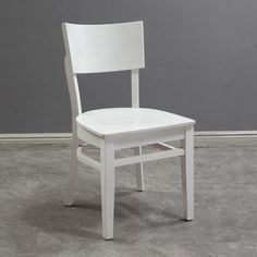 a white chair sitting on top of a cement floor next to a gray wall in an empty room