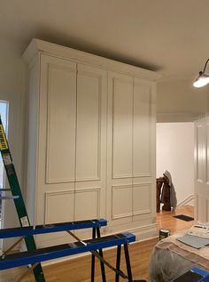 an empty room with white cabinets and blue ladders on the floor next to it