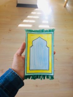 a person holding up a card with an image of a mosque on it in the middle of a room