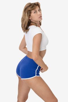 a woman in blue and white shorts posing for the camera with her hands on her hips