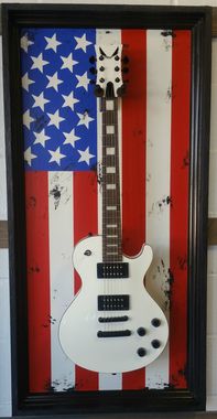 an electric guitar is displayed in front of the american flag on a white tile wall