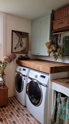 a washer and dryer in a small room next to a window with flowers