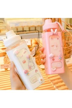 two water bottles are being held up in front of each other, one is pink and the other is white