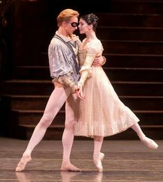 a man and woman in ballet clothes standing next to each other