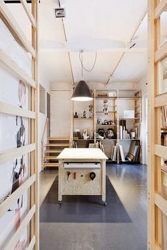 the room is full of shelves and pictures on the wall, with a workbench in the foreground