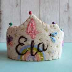 a white felt crown with the number forty five on it's side, decorated with colorful beads and sequins