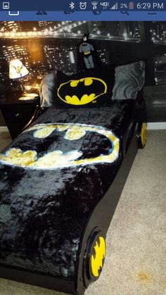 a batman themed bed with yellow and black decorations on the bottom, in a bedroom