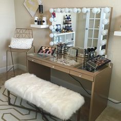 a vanity with a mirror, stool and makeup on it