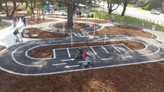 several children are playing in an outdoor play area with trees and grass on both sides