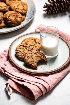 two cookies on a plate next to a glass of milk