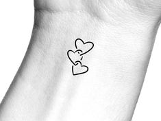 a small heart tattoo on the side of a foot with an outline of a person's face