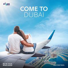 a man and woman sitting on the wing of an airplane looking out over a city