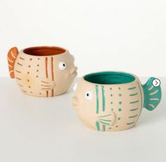 two ceramic fish mugs sitting next to each other