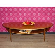 a wooden table with two apples on it and a pink wall in the back ground