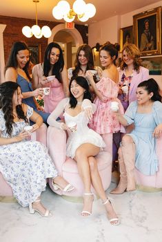 a group of women sitting on top of pink couches in a living room next to each other