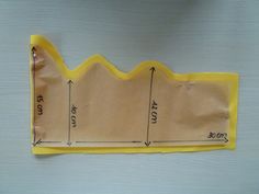 a piece of yellow material with measurements for the top and bottom part, on a white surface