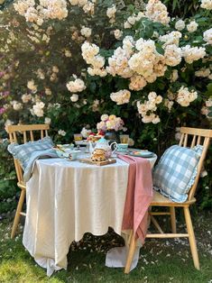 two chairs and a table with food on it in front of some white hydrangeas