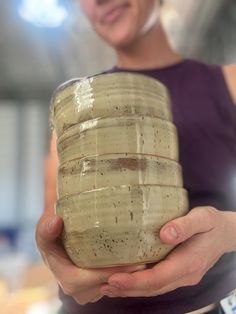 a woman is holding a ceramic container in her right hand and smiling at the camera