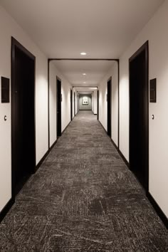 a long hallway with black doors leading to another room