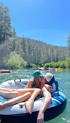 two people are laying on an inflatable boat and one is kissing the other