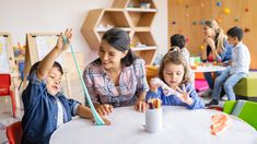 a woman and two children are sitting at a table with crayons in front of them